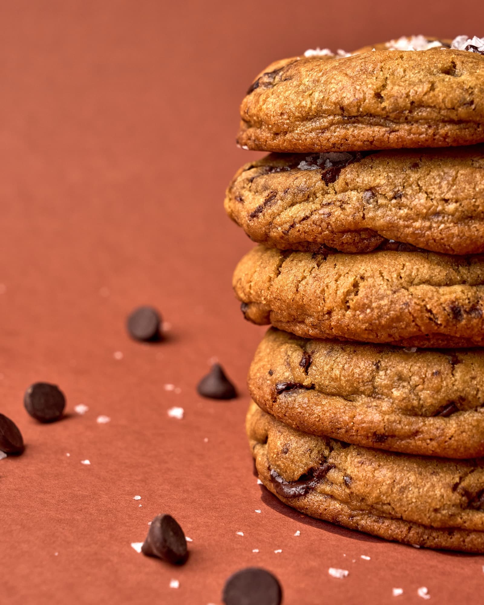 A stack of five Bad Boy cookies, flaky salt on top, on terracotta.